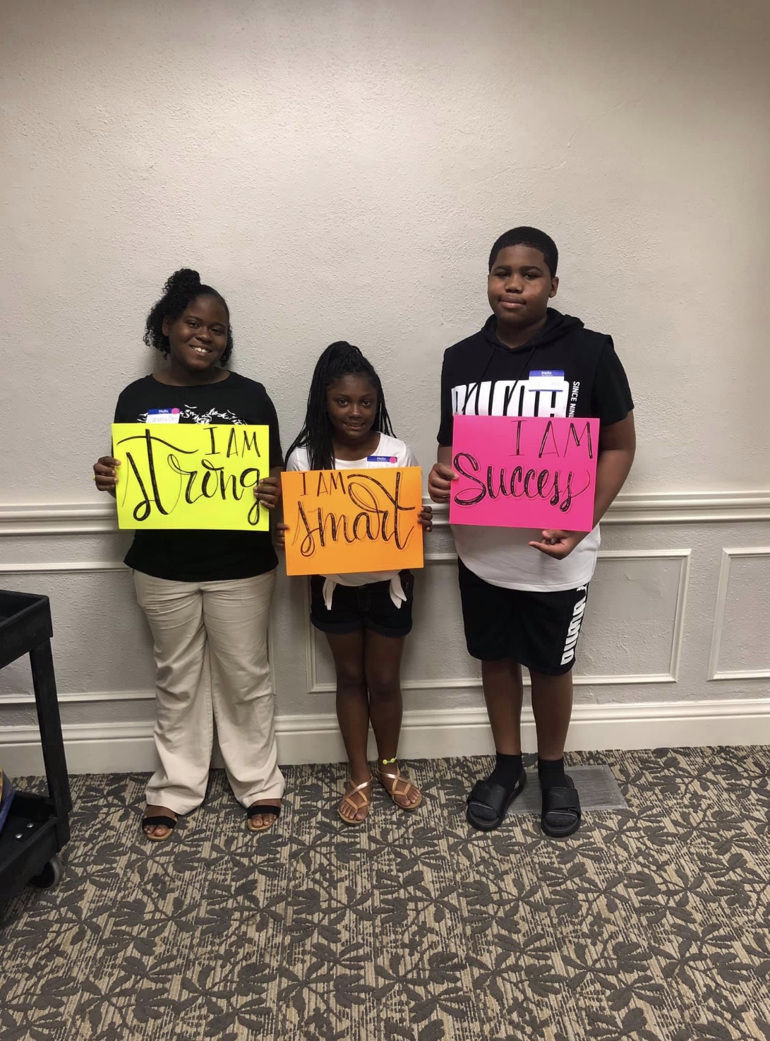 Three youth participants holding strength, impact and success signs